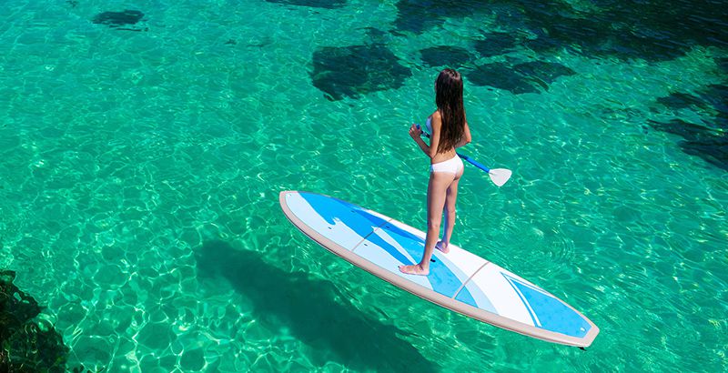 Young attractive woman in the sea on the Stand Up Paddle Board